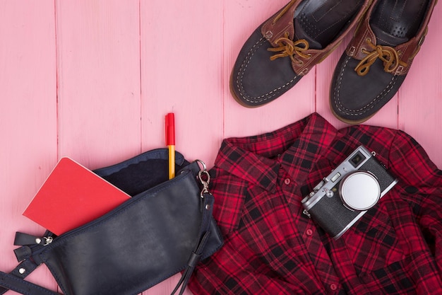 Tourist stuff bag camera shoes shirt note pad sur fond de bois rose