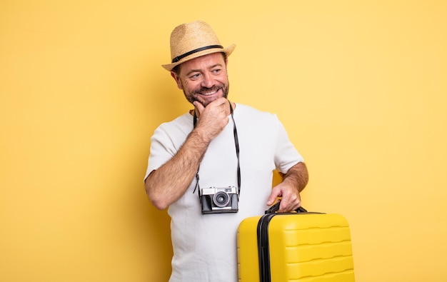 Touriste d'âge moyen souriant avec une expression heureuse et confiante avec la main sur le menton. concept de voyage