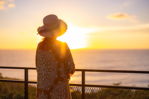Une touriste apprécie la vue sur la mer au coucher du soleil.