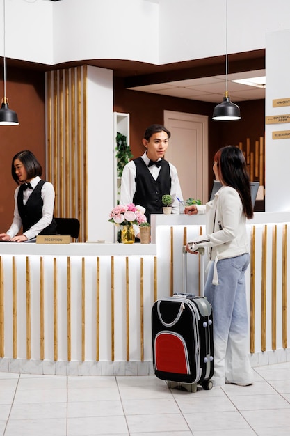 Touriste arrive à un complexe élégant et se prépare à faire l'enregistrement à la réception. l'invitée féminine est accueillie par le personnel sympathique et serviable à la reception de l'hôtel confortable.