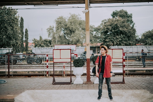 Un touriste asiatique attend un train à la gare de thaïlande homme hipster va voyager