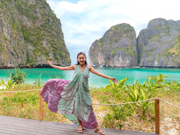 Touriste asiatique heureuse au point de vue de la terrasse en bois avec un beau paysage de la plage de la baie de Maya à l'endroit célèbre des îles Phi Phi Leh à Krabi Thaïlande mer turquoise avec des falaises dans l'océan