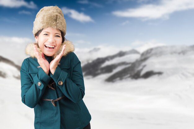 Touriste asiatique portant un manteau vert avec fond de montagne enneigée