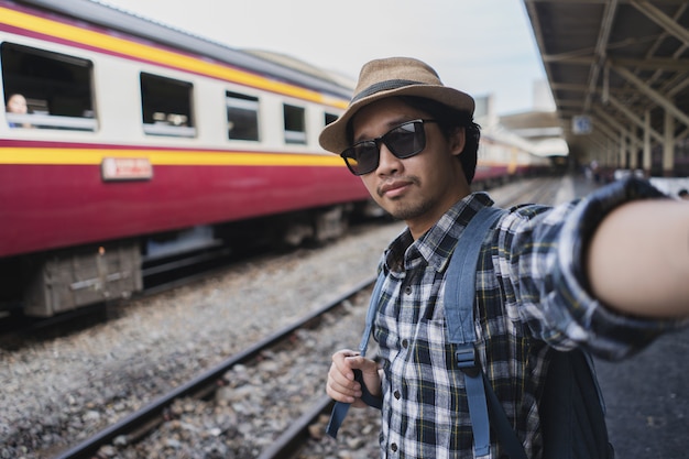 Photo touriste asiatique de sac de sac d'homme prennent un selfie dans la station de chemin de fer à la thaïlande.