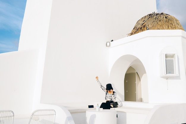 Touriste assis et levant les mains tout en regardant un bâtiment au dôme de chaume blanc