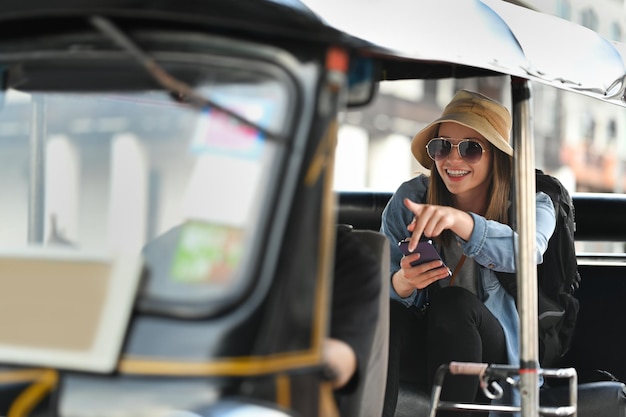 Touriste caucasien sorti avec des lunettes de soleil assis sur le siège arrière du transport public Tuk Tuk en Thaïlande