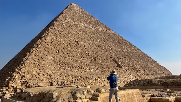Touriste avec un chapeau photographiant une pyramide en Égypte