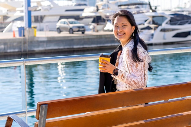 Touriste chinois souriant assis sur un banc avec le port en arrière-plan