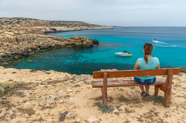 Le touriste de CHYPRE s'assied sur un banc en bois près de la lagune bleue