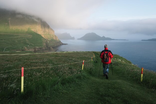 Un touriste fait une randonnée dans le village de Gasadalur, aux îles Féroé.