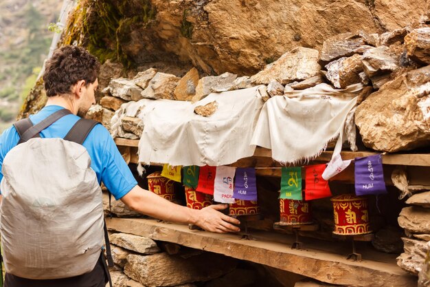 Un touriste fait tourner des moulins à prières colorés sur un sentier dans l'Himalaya