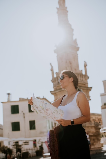 Touriste féminine avec un plan de la ville près de la statue de Saint Oronzo à Ostuni Italie