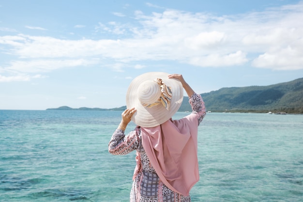 Touriste de femme dans le chapeau d'été posant la pose arrière avec le beau paysage marin d'eau claire à Karimun Jawa Isl