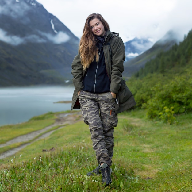 Touriste fille dans des vêtements chauds à l'aube dans le contexte du lac de brouillard et des montagnes bleues