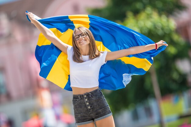 Touriste de fille heureuse marchant dans la rue avec le drapeau suédois.