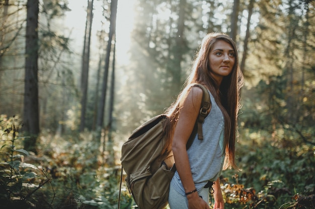 Touriste fille hipster avec sac à dos voyage dans les bois