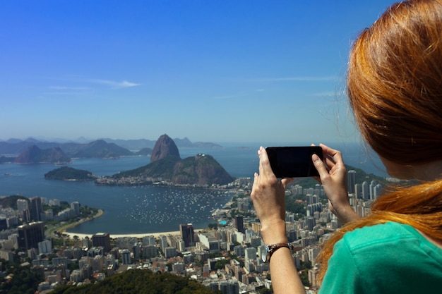 Touriste de fille prenant une photo sur un smartphone Pao de Acucar. Rio de Janeiro.