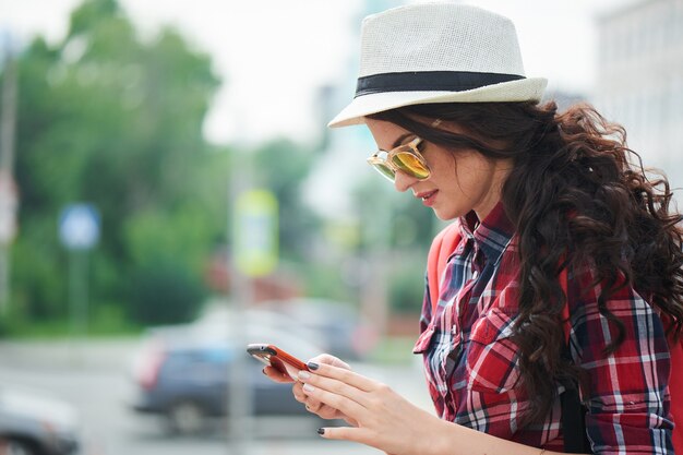 Touriste de fille tenant un téléphone portable à l'arrière-plan de la ville