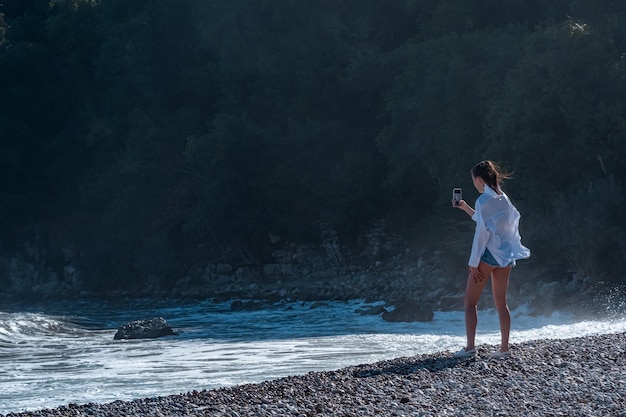 Une touriste filme un surf orageux par jour de vent parmi la poussière d'eau