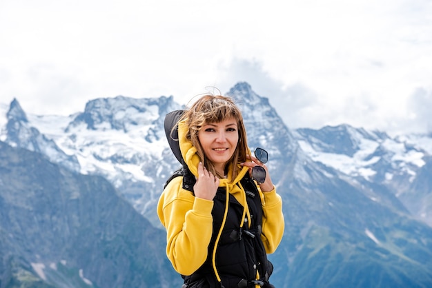 Une touriste heureuse en trekker lève les mains pour célébrer le succès au sommet de la falaise