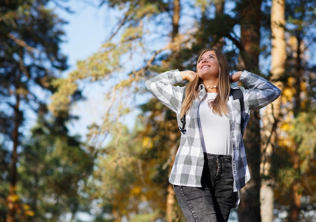 une touriste heureuse va camper à travers la forêt en levant les mains et en souriant