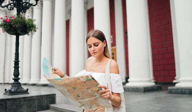 Touriste jeune beauté femme explorer le plan de la ville en milieu urbain contre les colonnes