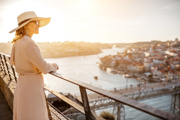 Touriste de jeune femme appréciant la belle vue aérienne de paysage urbain avec le pont célèbre pendant le coucher du soleil dans la ville de Porto, Portugal