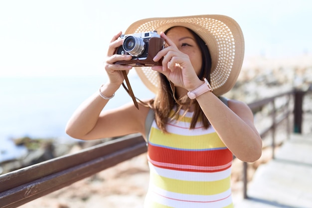 Touriste de jeune femme asiatique utilisant un appareil photo vintage au bord de la mer