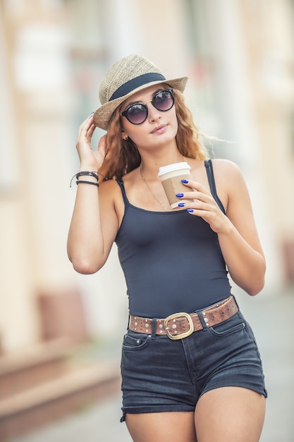 Touriste de jeune femme blonde buvant du café quelque part dans les rues de la ville.