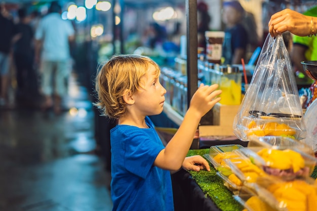 Touriste de jeune garçon sur le marché alimentaire asiatique de la rue piétonne