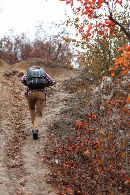 Photo touriste de jeune homme avec le sac à dos marchant sur la nature