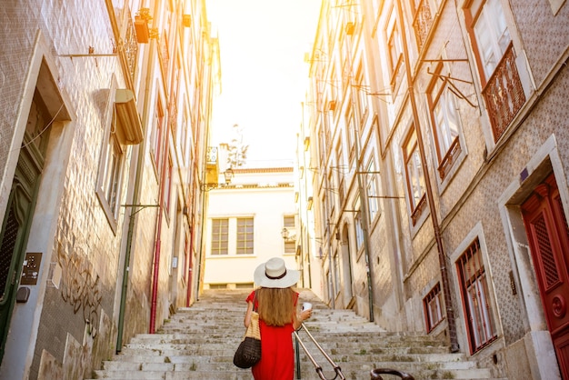 Touriste marchant en arrière sur la rue étroite dans la région d'Alfama pendant la lumière du matin à Lisbonne, Portugal