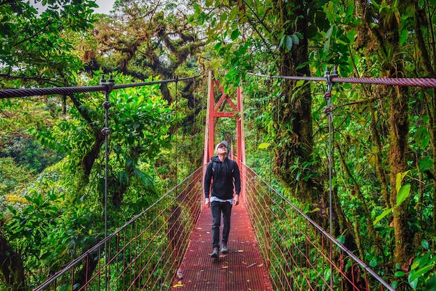 Touriste marchant sur un pont suspendu dans la forêt de nuages de monteverde costa rica