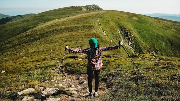 Photo une touriste marche sur un sentier de randonnée sur fond de montagnes verdoyantes