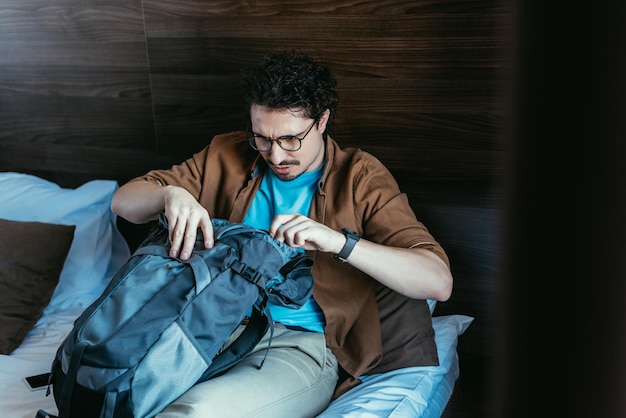 Touriste masculin regardant dans le sac à dos dans la chambre d'hôtel