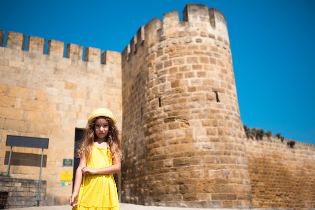 Une touriste portant un chapeau jaune et une robe d'été se promène dans la rue de la vieille ville en pierre avec une forteresse Visite guidée L'enfant s'est perdu à la recherche de ses parents