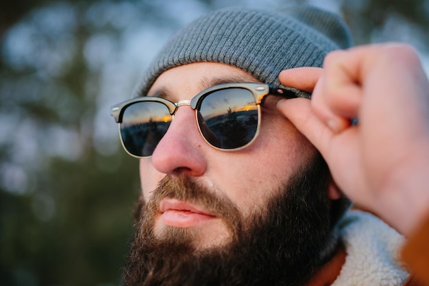 Un touriste regarde le coucher du soleil en grimpant dans les montagnes d'hiver dans des verres reflétant le ciel