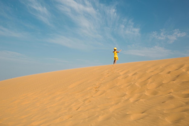 Une touriste en robe jaune court le long d'une dune de sable dans le désert Sites touristiques du Daghestan Sarykum dune