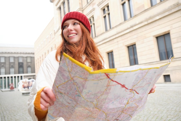 Photo une touriste rousse explore la ville regarde une carte papier pour trouver un chemin pour les monuments historiques