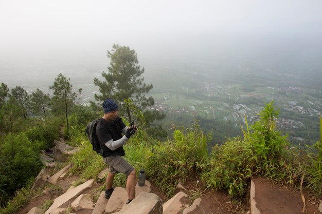 Touriste avec sac à dos prend des photos avec un téléphone intelligent dans les montagnes