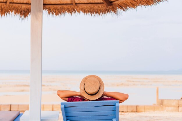 Un touriste se prélasse sur une chaise de plage au bord de la mer en été avec fond de ciel bleu. Concept de voyage heureux le week-end.