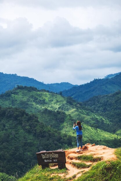 Une touriste utilisant un smartphone pour prendre une photo d'une belle chaîne de montagnes