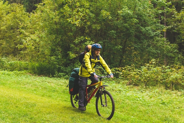 Un touriste à vélo masculin traverse la forêt d'automne