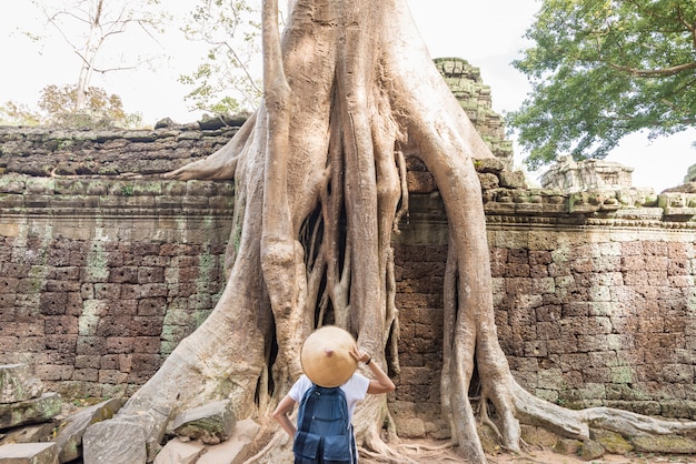 Un touriste visitant les ruines d’Angkor au milieu de la jungle, complexe de temples d’Angkor Wat, destination de voyage au Cambodge. Femme, chapeau traditionnel, vue postérieure