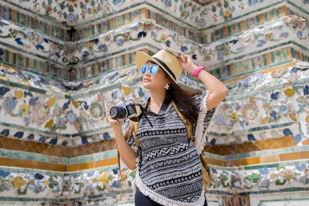 Une touriste voyage et fait du tourisme à l'intérieur de Wat Arun sur le fleuve Chao Phraya à Bangkok en Thaïlande Elle avait un appareil photo une carte un chapeau de paille des lunettes de soleil