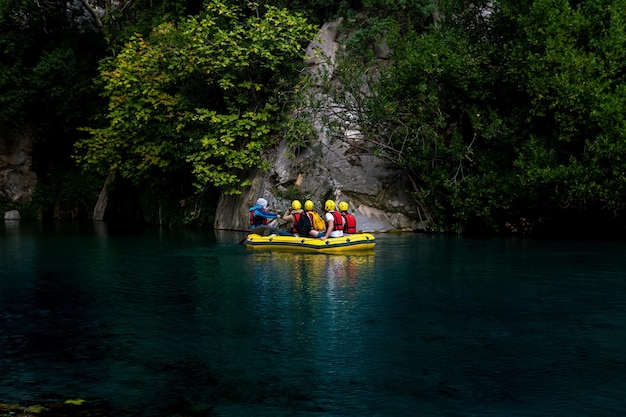 Les touristes sur un bateau gonflable flottent dans un canyon rocheux avec de l'eau bleue à Goynuk Turquie