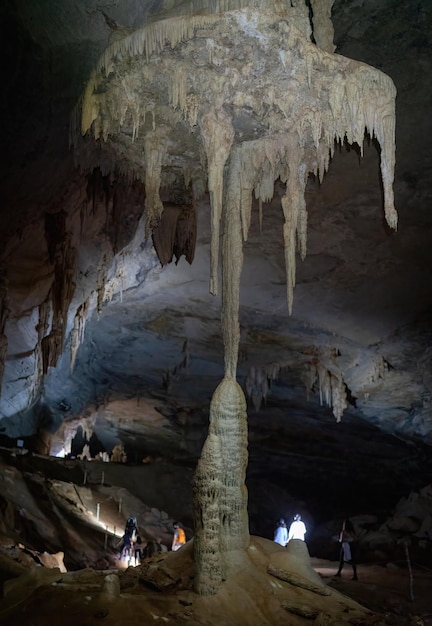 Photo les touristes excités par l'union des stalactites et des stalagmites dans l'union de la lampe