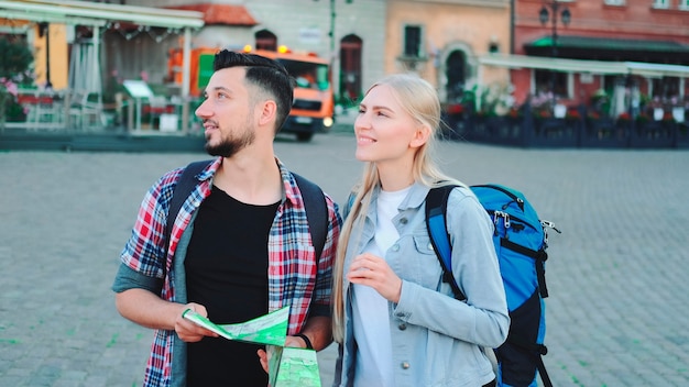 Touristes d'homme et de femme avec la carte recherchant le nouveau lieu historique au centre de la ville