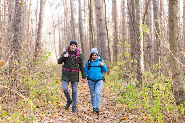 Touristes marchant dans le parc avec sac à dos vêtus de vestes bleues et noires.