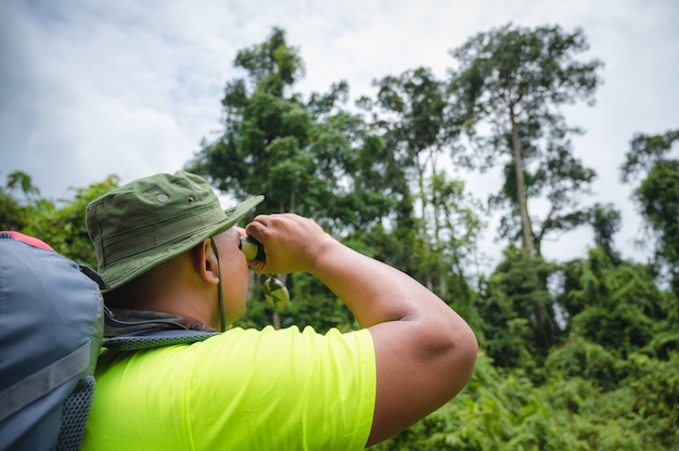 Touristes observant le calao et le singe d'oiseau avec des jumelles dans la forêt tropicale. Parc national de Khao Yai, Thaïlande. Visite d'observation d'oiseaux, de calaos et de singes. Image du concept d'écotourisme.